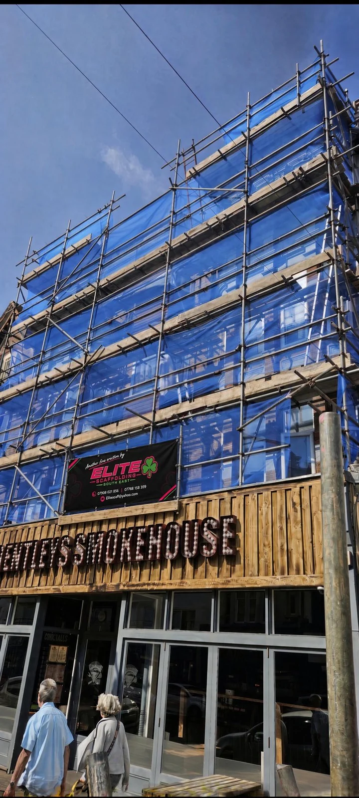 Debris-netted scaffold over Bentley's Smokehouse in Hastings, Elite banner on the lift