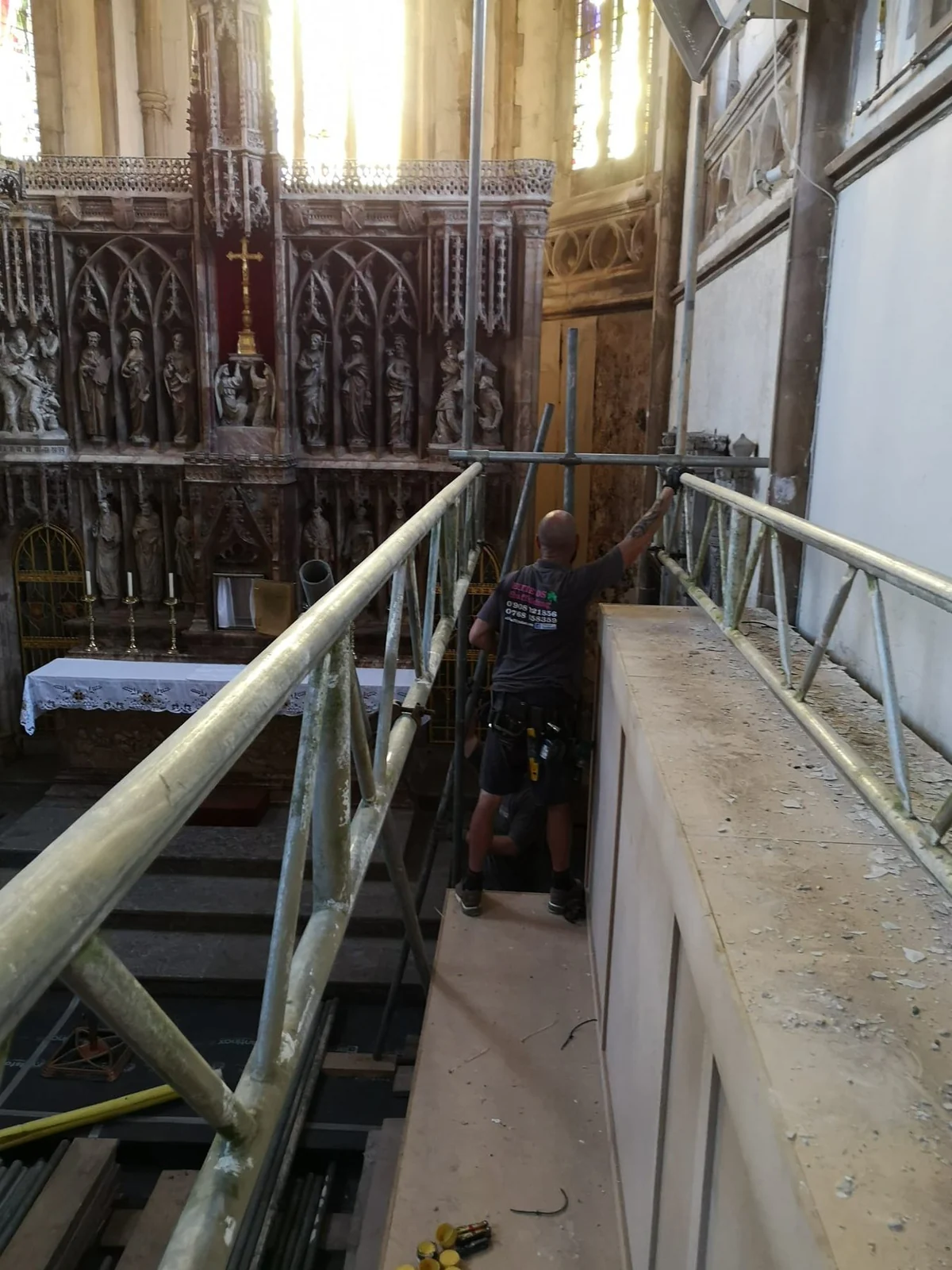 Scaffolder on an internal lift in front of a church reredos